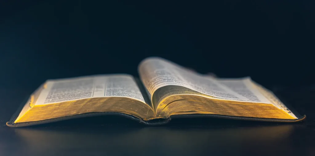 Una Biblia abierta con cantos dorados sobre un fondo azul oscuro